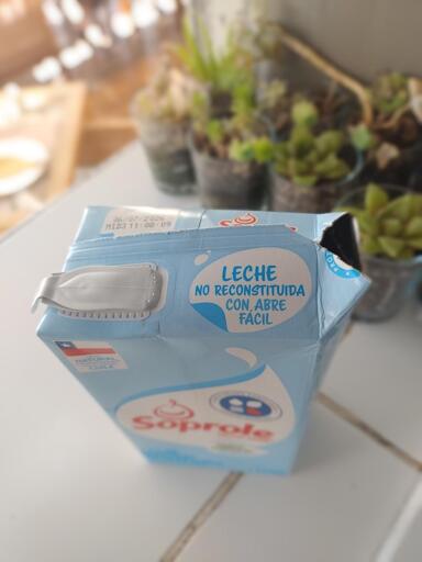 Un cartón de leche con apertura fácil sin utilizar que se ha abierto por el otro lado con un corte en el tetrabrick.